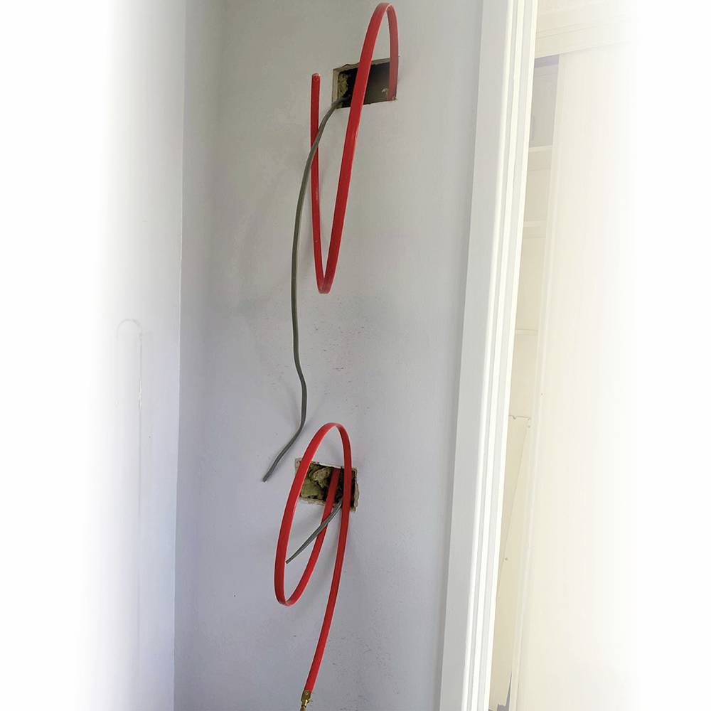 Zwei Wandöffnungen mit herausragenden roten und grauen Kabeln, vorbereitet für Elektroinstallationen.