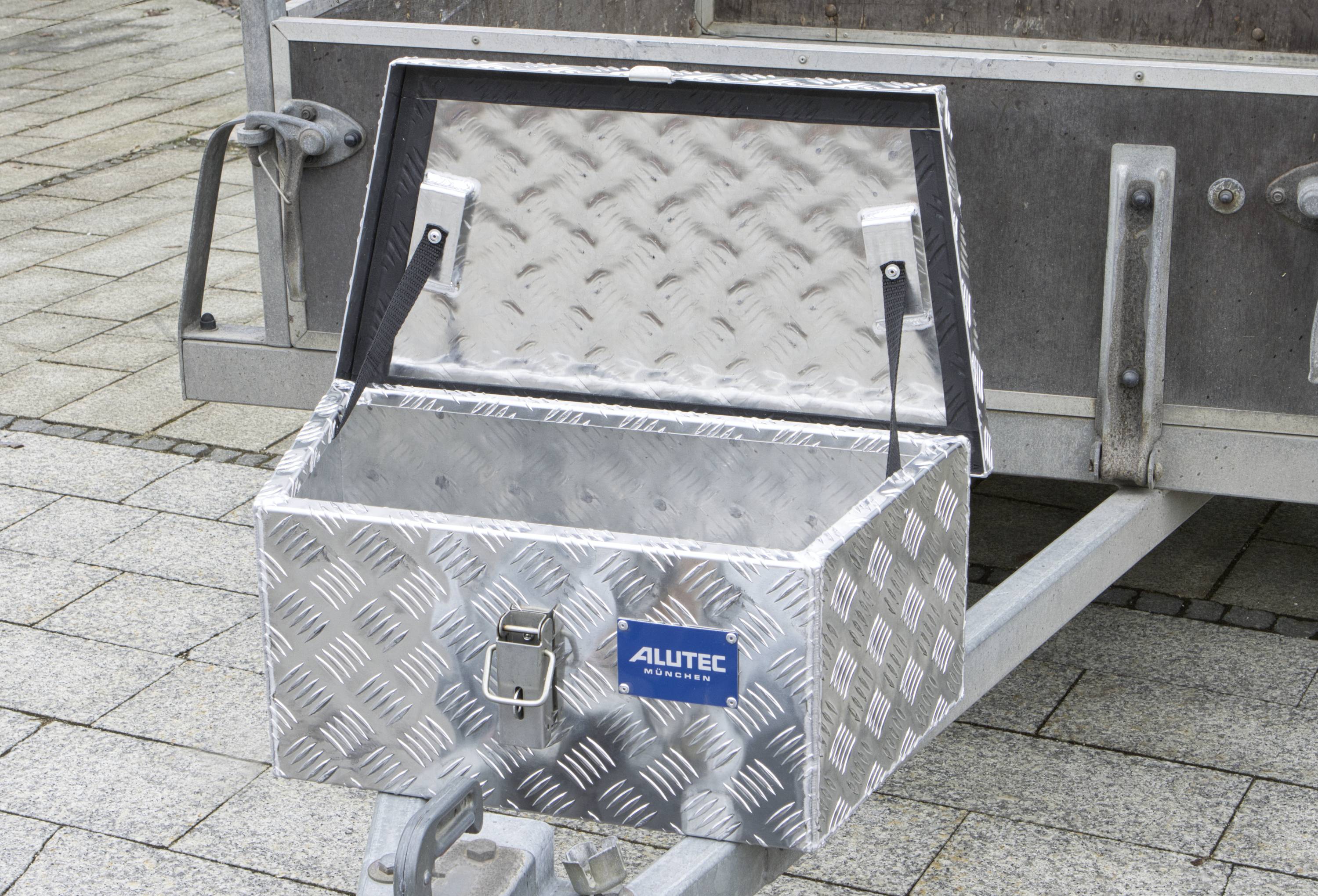 Alu-Werkzeugkasten auf einem Anhänger, geöffnet und leer. Silberne Riffelblech-Oberfläche, Herstellerlogo 'Alutec' sichtbar.