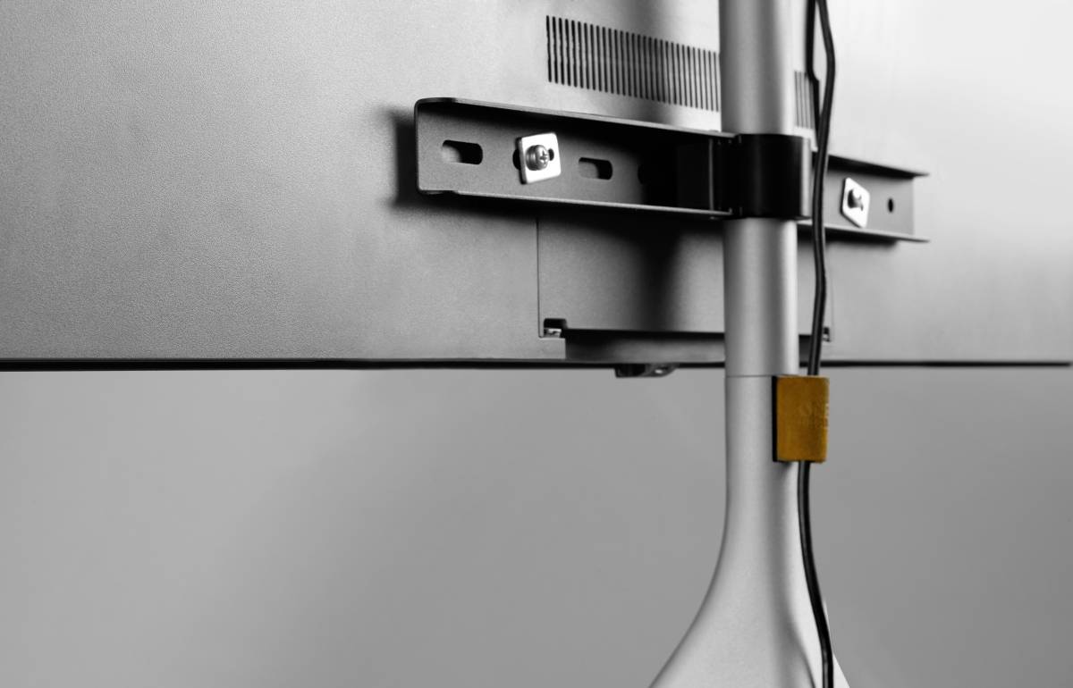 Rückseite eines Monitors mit Wandhalterung und verkabelten Ständer.