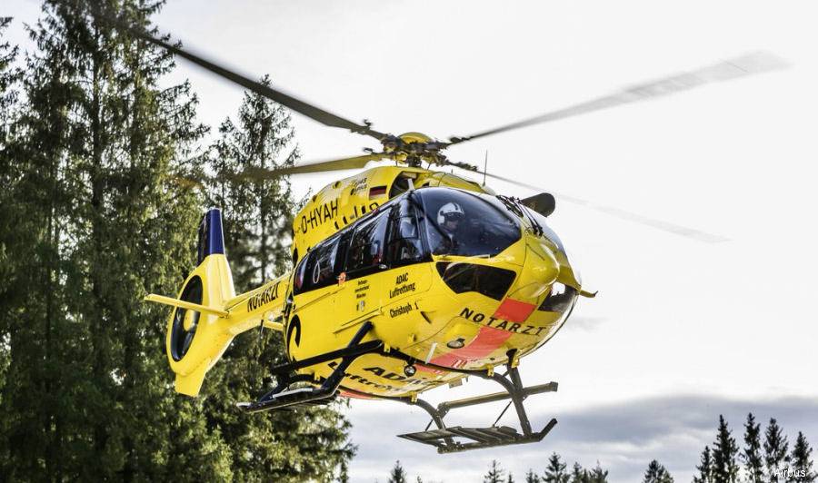 Ein gelber Rettungshubschrauber mit der Aufschrift 'Notarzt' fliegt über bewaldetes Gebiet, bereit für einen medizinischen Einsatz.