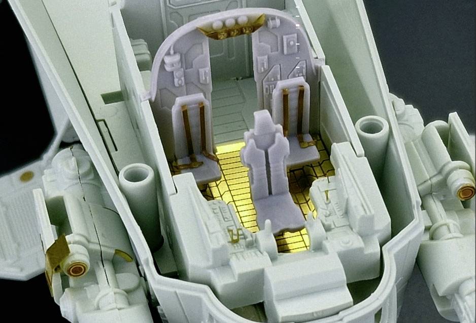 Cockpit eines detailreichen Modellraumschiffs mit sichtbarem Pilotensitz, goldenen Bodenakzenten und Instrumentenanzeigen.