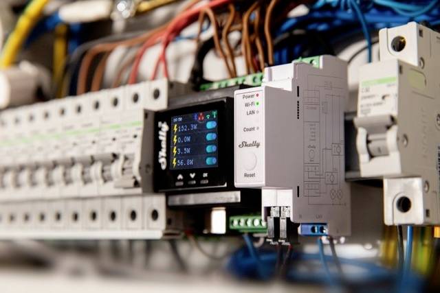 Nahaufnahme eines modernen Sicherungskastens mit digitalen Anzeigen. Verschiedene Drähte sind verbunden, und Werte sind auf einem Display sichtbar.