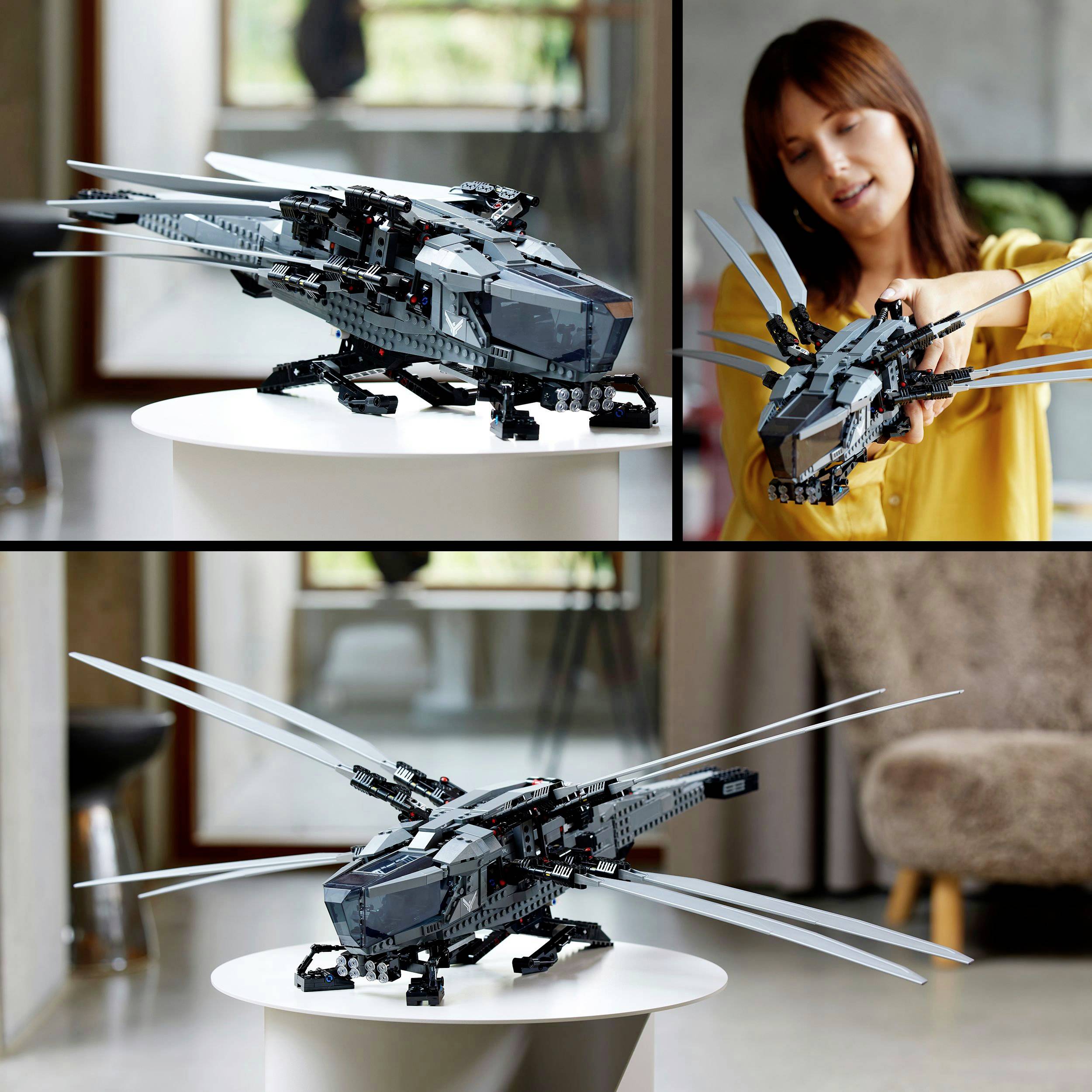 Ein Spielzeug-Helikopter aus Bausteinen ist auf einem Tisch ausgestellt. Eine Frau lächelt und zeigt auf das Modell.