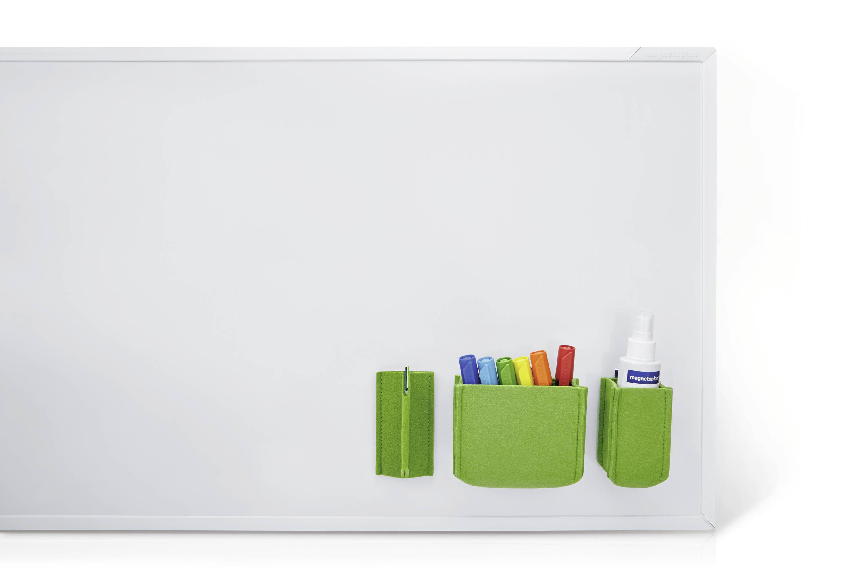 Weiße Tafel mit grünen Haltern für Stifte und Spray, links leer, rechts Zubehör zum Schreiben und Reinigen.