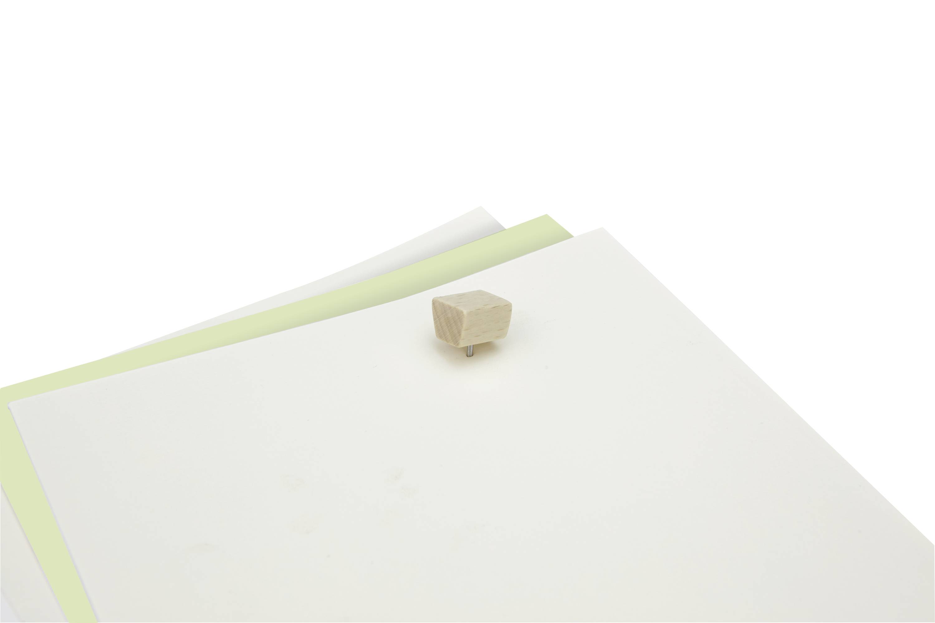 Ein Stapel weißes und grünes Papier liegt auf einem Tisch. Auf den Blättern befindet sich ein kleiner, rechteckiger Holzblock.