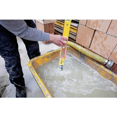 Eine Person hält eine Wasserwaage in eine mit Wasser gefüllte Schubkarre auf einer Baustelle, um die Nivellierung zu überprüfen.