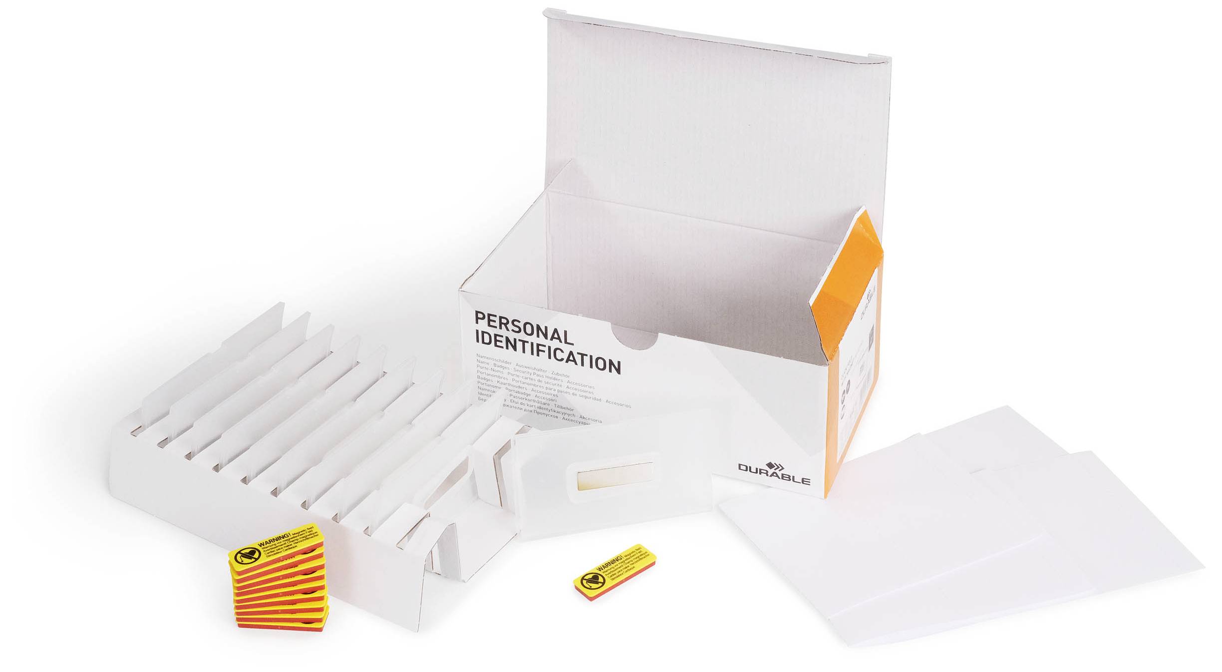 Eine offene, weiße Box mit 'Personal Identification'-Aufdruck, enthält Fächer/Laschen. Zwei gelb-rote Marken sind daneben platziert.