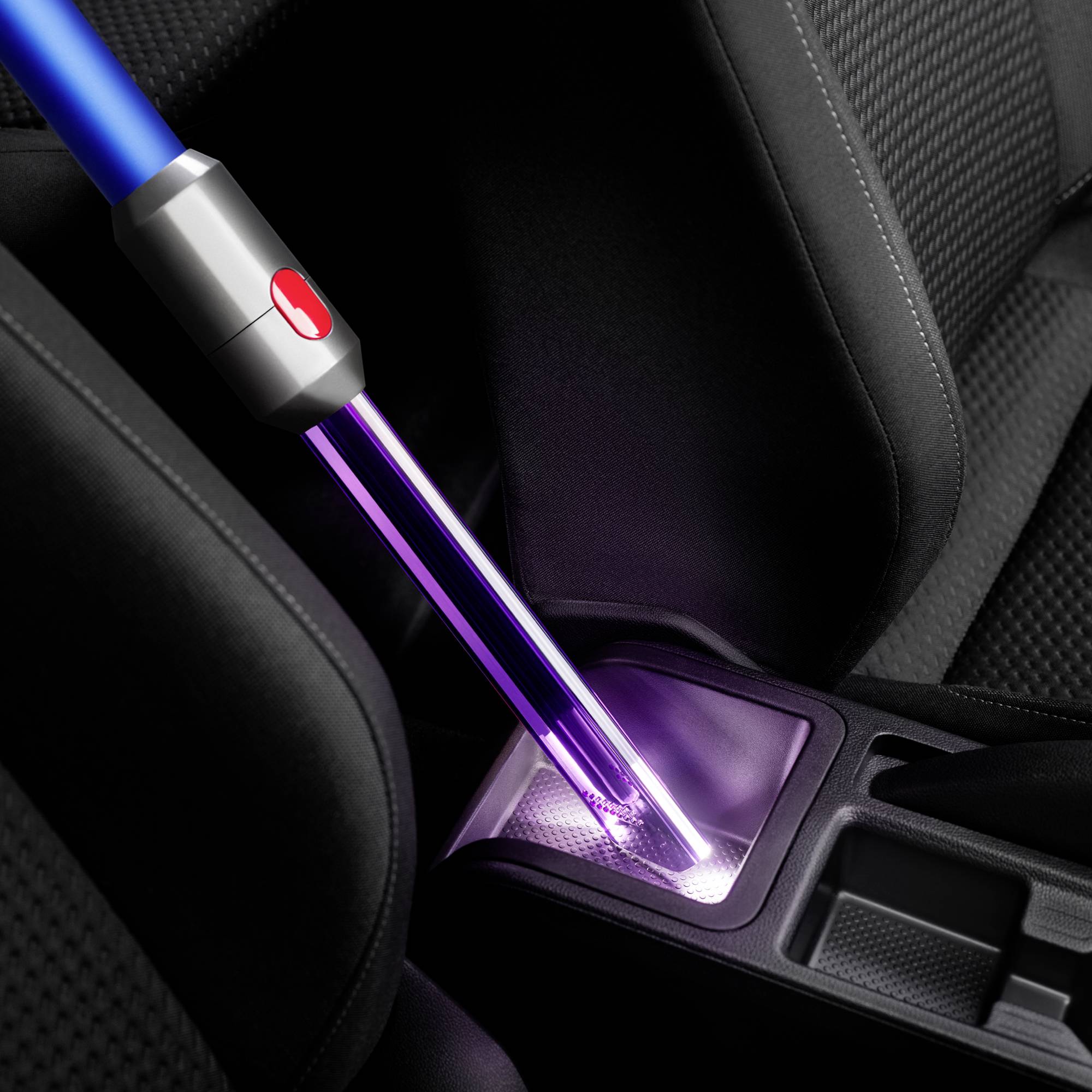 Reinigung eines Autositzspaltes mit einem violetten Lichtgerät, das Schmutz und Staub entfernt.