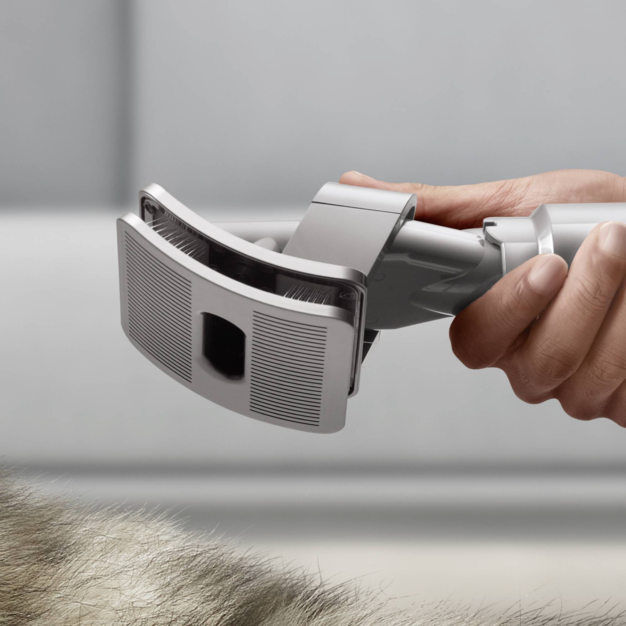 Hand führt moderne Fellbürste über das Fell eines Tieres, Fokus auf die Bürste.