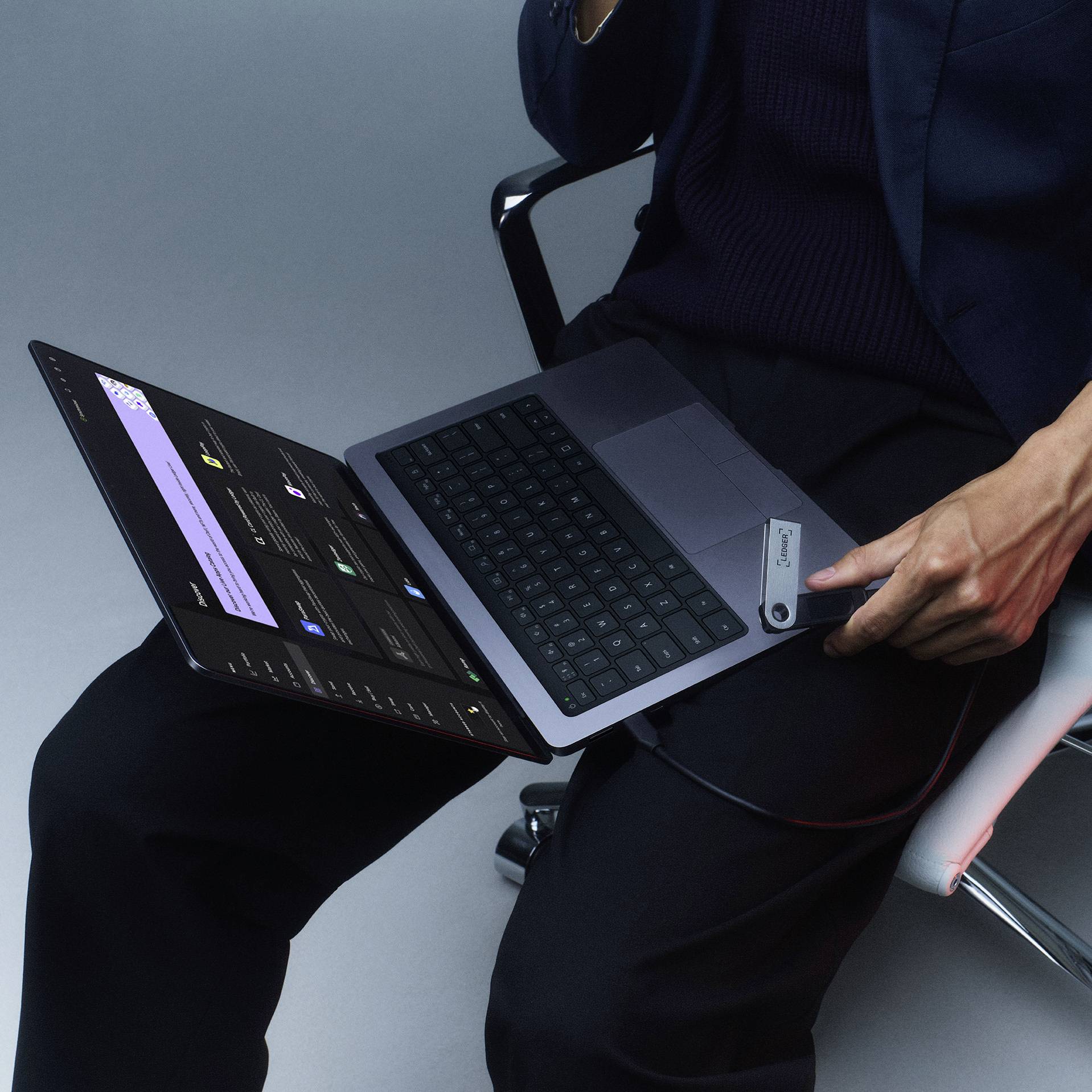 Eine Person sitzt auf einem Stuhl und nutzt ein Laptop im Tablet-Modus. Der Bildschirm zeigt eine App mit dunkler Benutzeroberfläche.