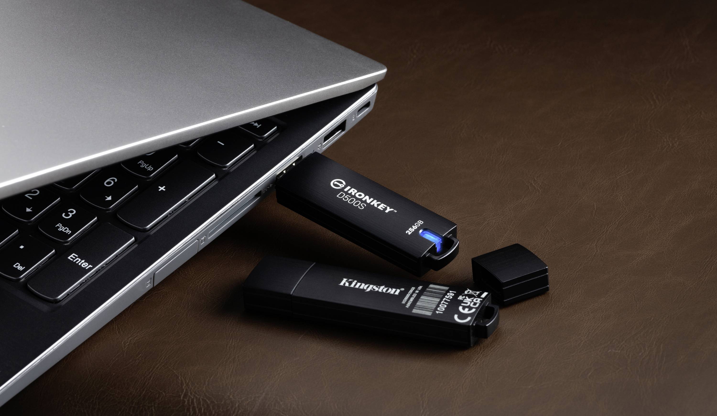Ein Laptop mit zwei USB-Sticks daneben. Einer der Sticks ist an den Laptop angeschlossen, der andere liegt daneben auf einem Tisch.
