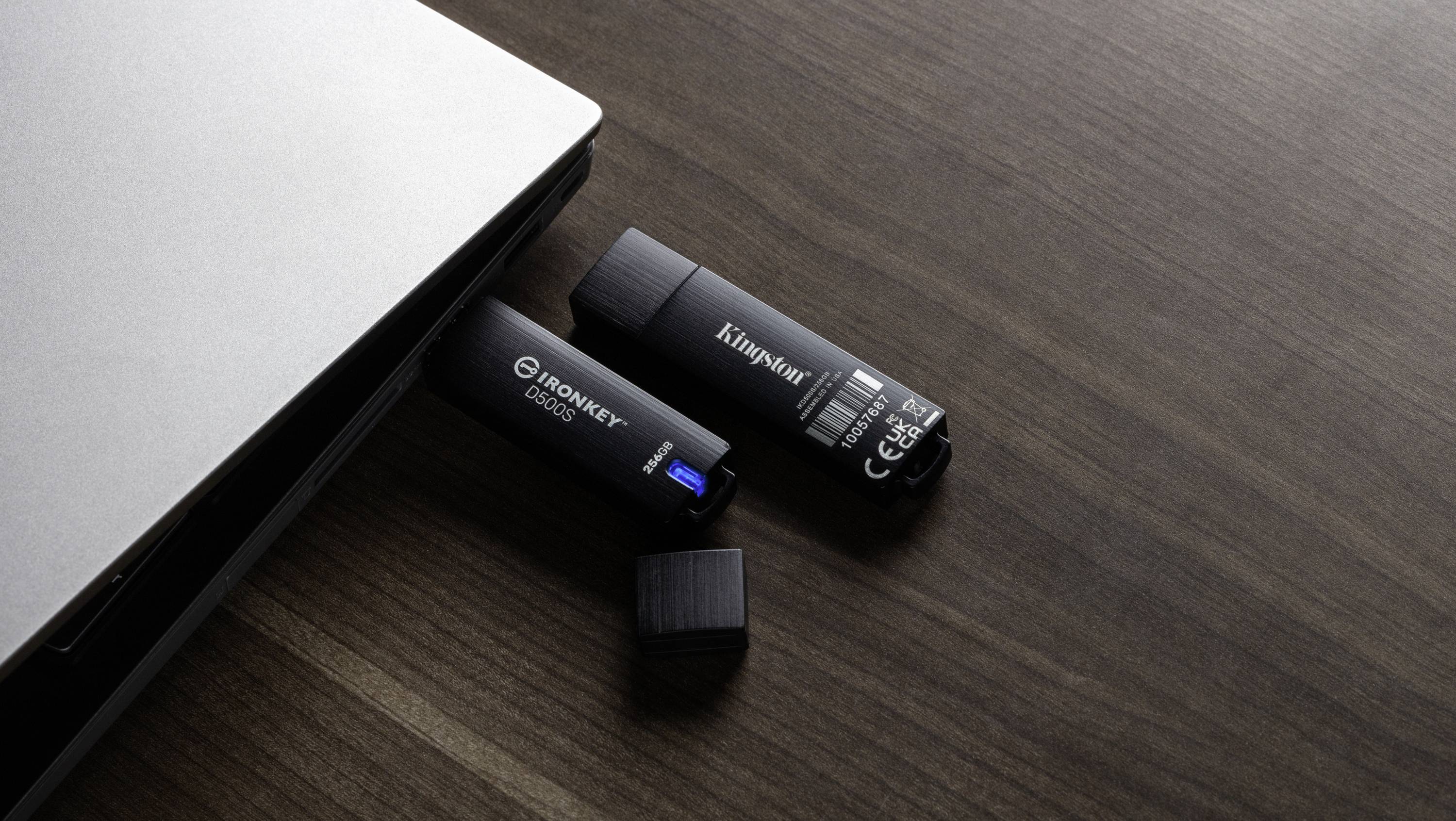 Ein Laptop neben zwei USB-Sticks auf einem Holztisch. Einer der Sticks ist geöffnet, der andere verschlossen.