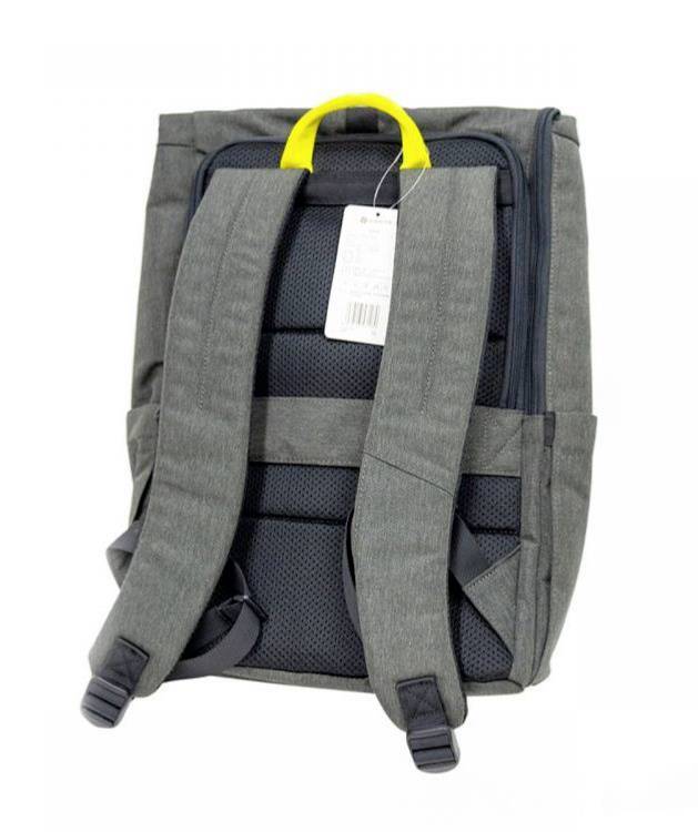 Ein grauer Rucksack mit gepolsterten Schulterriemen und einem gelben Griff. Ein Etikett ist an der oberen Schlaufe befestigt.