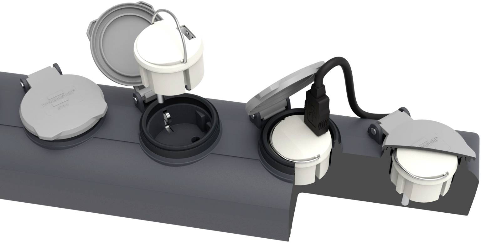Vier Steckdosen mit Schutzkappen, zwei geöffnet und mit einem Stecker verbunden. Sie sind auf einer grauen Leiste montiert.