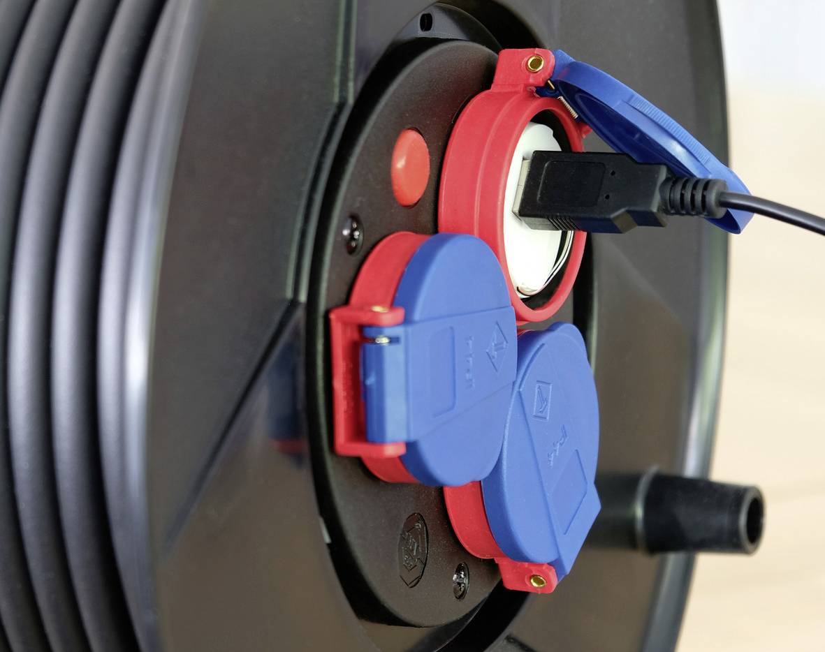 Nahaufnahme eines Kabeltrommelanschlusses mit blauen und roten Steckdosen, ein Kabel ist eingesteckt.