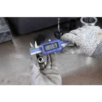 Eine Person trägt Handschuhe und misst den Durchmesser eines Metallstücks mit einem digitalen Messschieber. Der Bildschirm zeigt '17,76'.