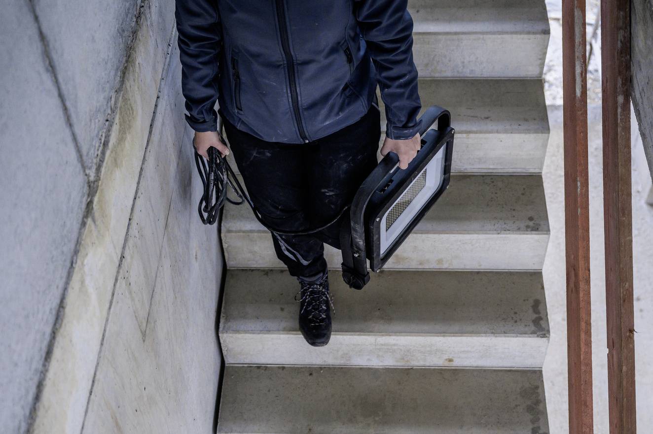 Person trägt einen Laptop die Treppe hinunter.
