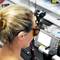 Eine Person in einem Hightech-Labor trägt Schutzbrille und arbeitet mit einem optischen Gerät. Im Hintergrund stehen elektronische Messgeräte.