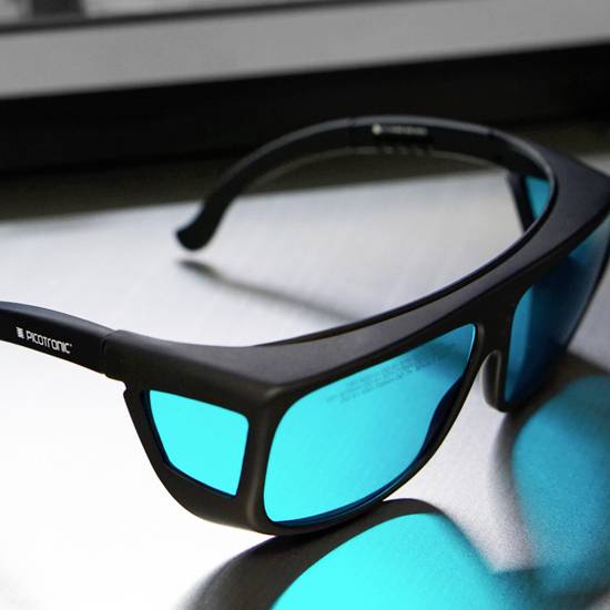 Schwarze Sportsonnenbrille mit blauen Gläsern liegt auf einem Tisch. Reflektion auf der Oberfläche sichtbar.