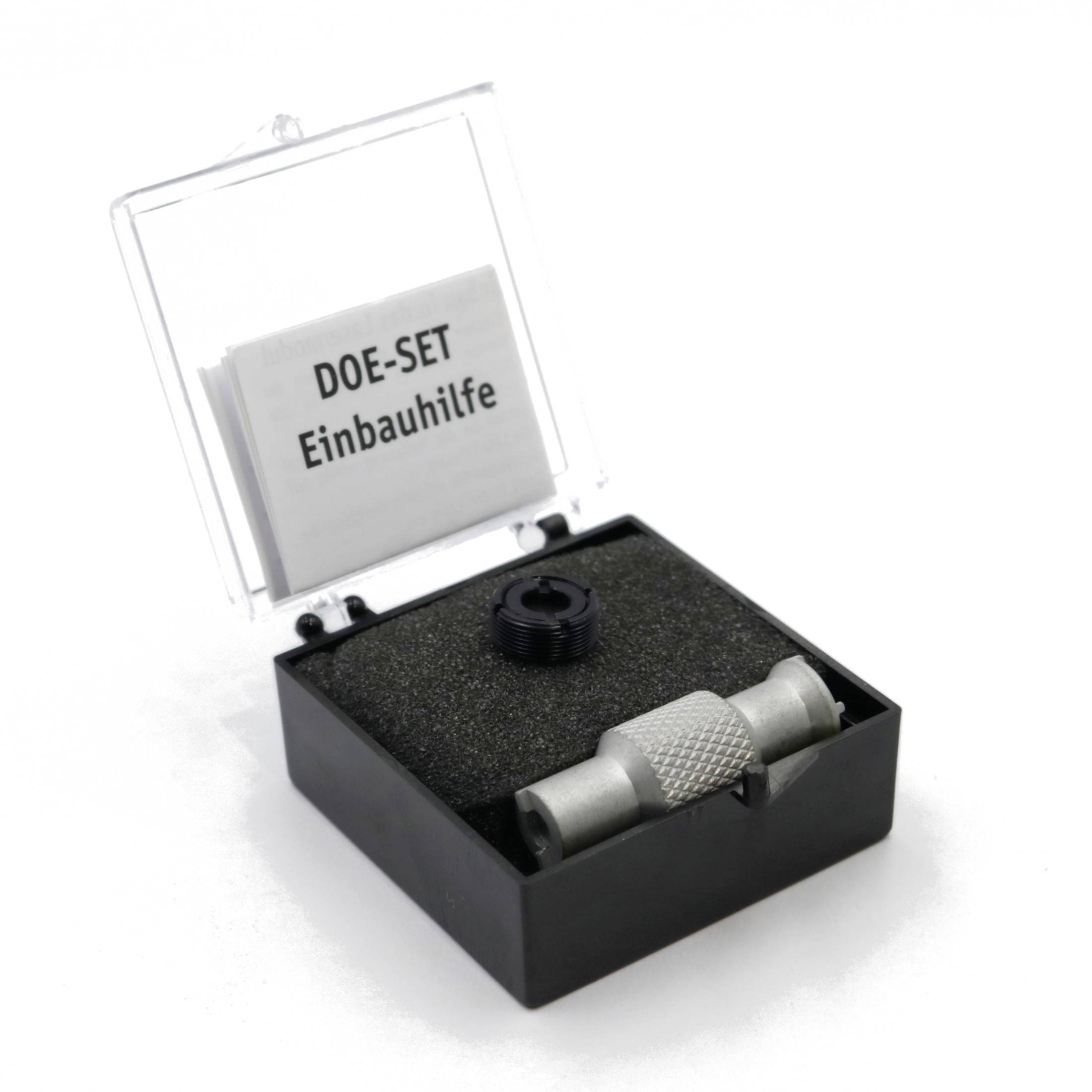 'DOE-SET Einbauhilfe' in einer offenen schwarzen Box mit Schaumstoffeinlage. Enthält ein metallisches Werkzeug und Papier.
