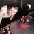 Eine Frau arbeitet in einem Labor mit einem Laserexperiment, bei dem rote Laserstrahlen über einen Tisch mit verschiedenen optischen Geräten verlaufen.