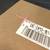 Ein Paket wird von einem Barcode-Scanner erfasst. Aufkleber zeigt eine Seriennummer und Barcode.