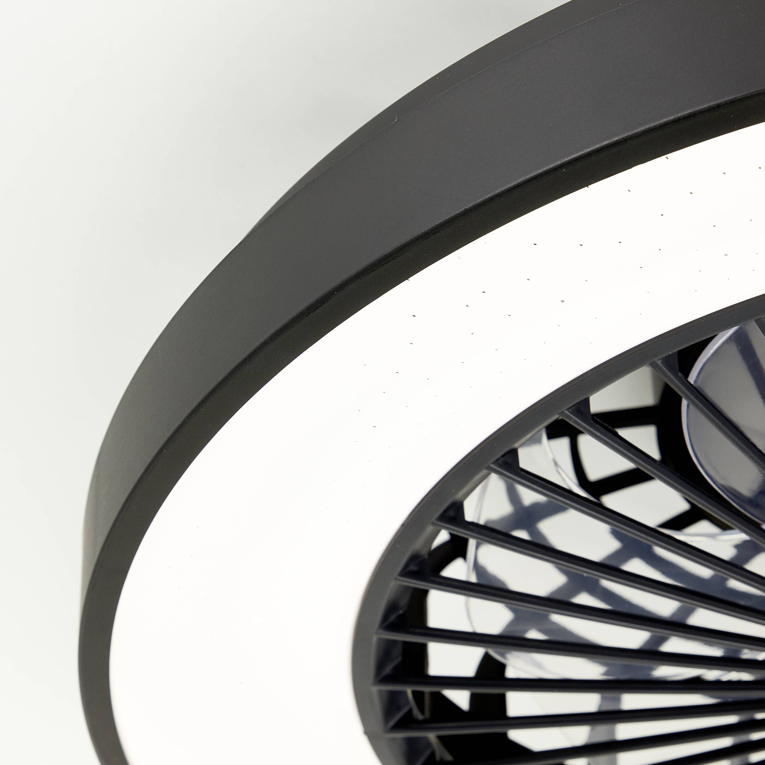 Runde Deckenleuchte mit schwarzem Rahmen und integriertem Ventilator. Moderne, minimalistische Gestaltung für zeitgemäße Innenräume.