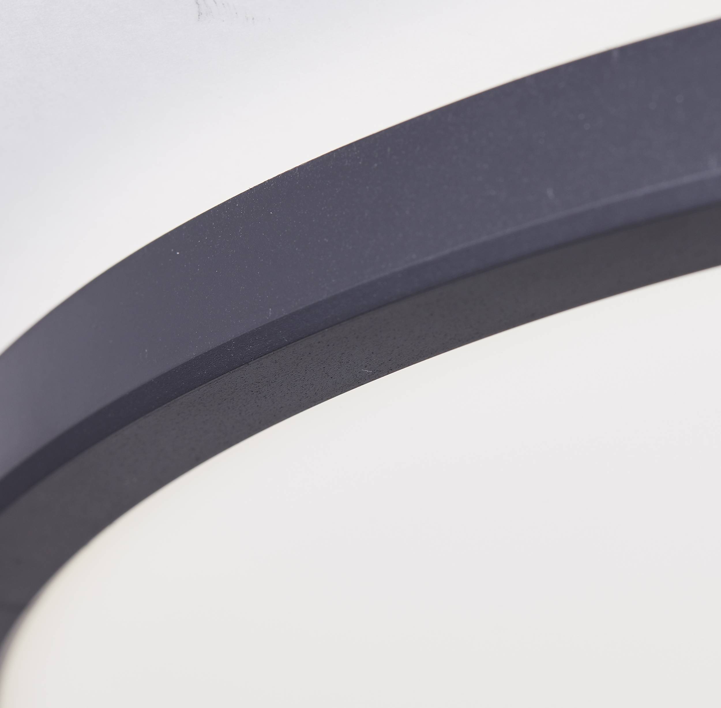 Nahaufnahme einer runden, dunklen Kante, möglicherweise ein Teil eines Gehäuses oder Rahmens. Der Hintergrund ist unscharf.