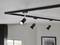 Schwarze Deckenlampe mit vier verstellbaren Spotlights. Moderne Inneneinrichtung. Hintergrund: Fenster und gerahmtes Bild.