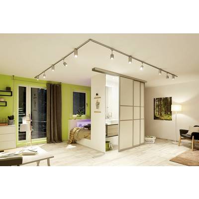Ein modernes Wohnzimmer mit hellen Farben. Links ein Schreibtisch und Bücherregale, rechts ein Sofa und Lampe. Schlafzimmer durch Schiebetür getrennt.