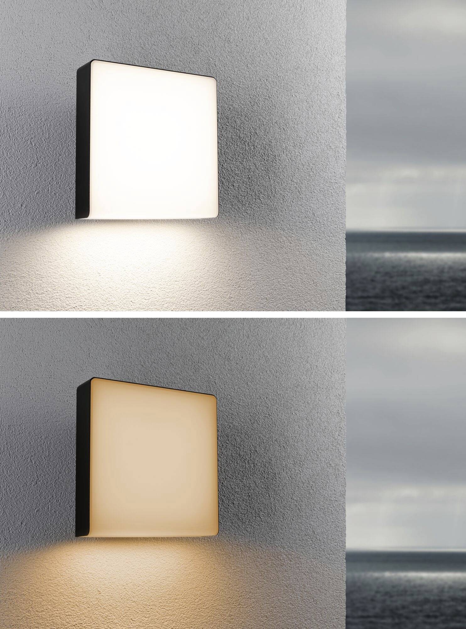 Zwei identische quadratische Außenleuchten an einer Wand; obere leuchtet weiß, untere warmweiß. Im Hintergrund Meerblick bei bewölktem Himmel.