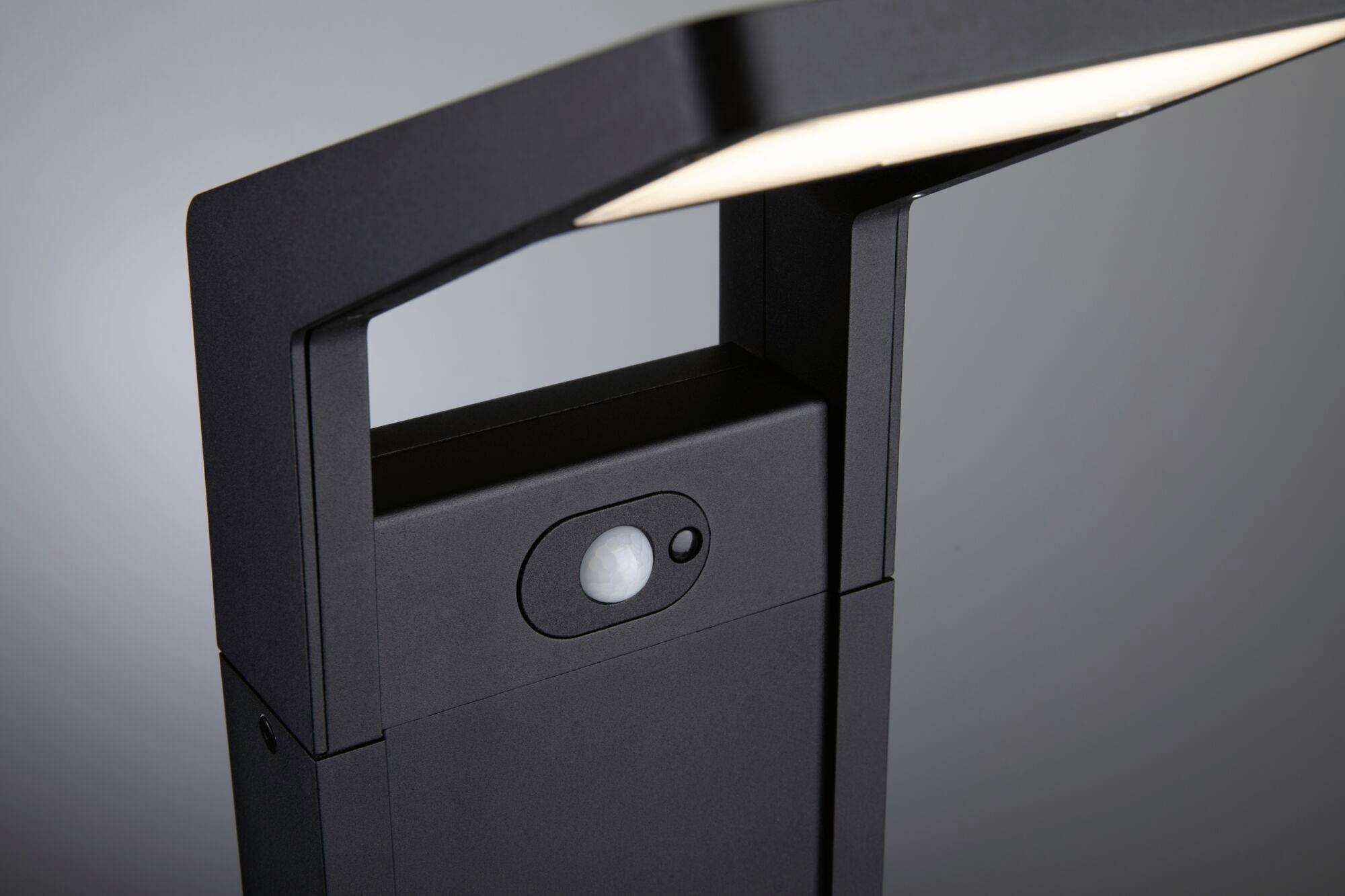 Schwarzes, modernes Gartenlicht mit Bewegungsmelder und rechteckigem, beleuchtetem Schirm, vor grauem Hintergrund.