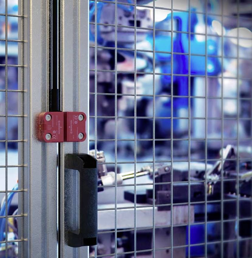 Sicherheitsverriegelung an einem Maschinenschutztor, im Hintergrund industrielle Geräte in einer Produktionsumgebung.