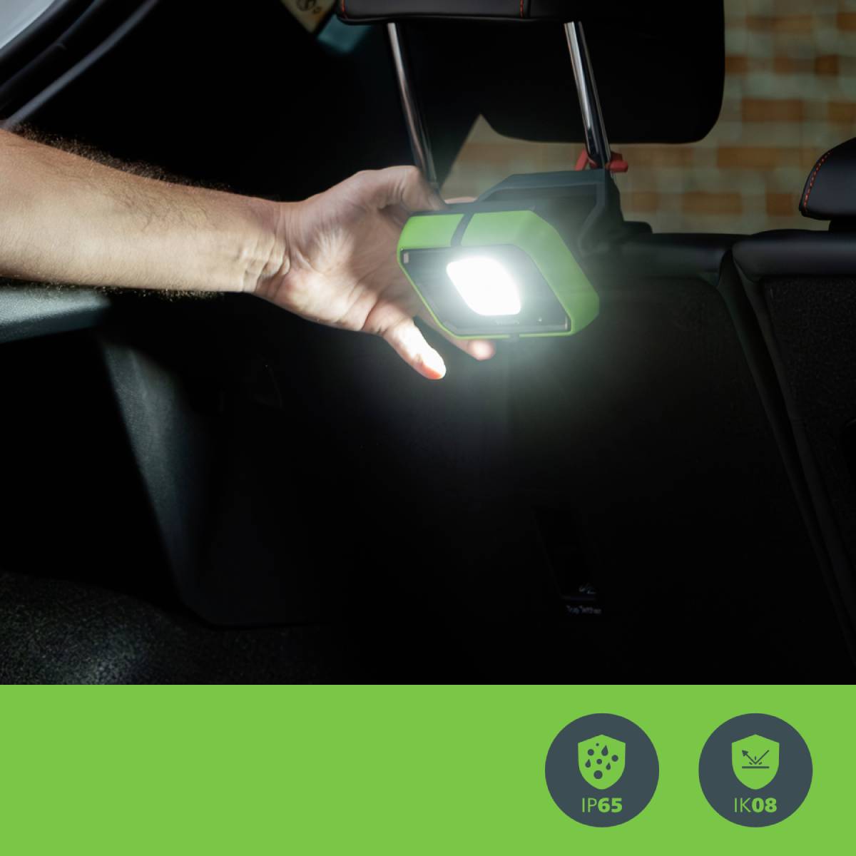 Hand hält eine kompakte, leuchtende Lampe im Auto. Symbole darunter zeigen Schutzart IP65 und Stoßfestigkeit IK08 an.