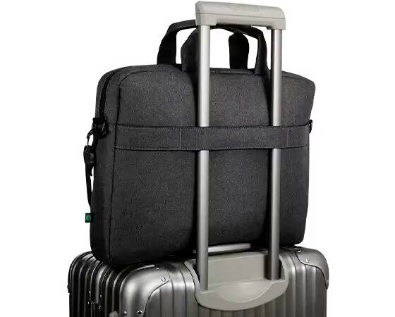 Eine schwarze Laptoptasche sitzt auf einem silbernen Rollkoffer. Die Tasche ist an den Griffen des Koffers befestigt.