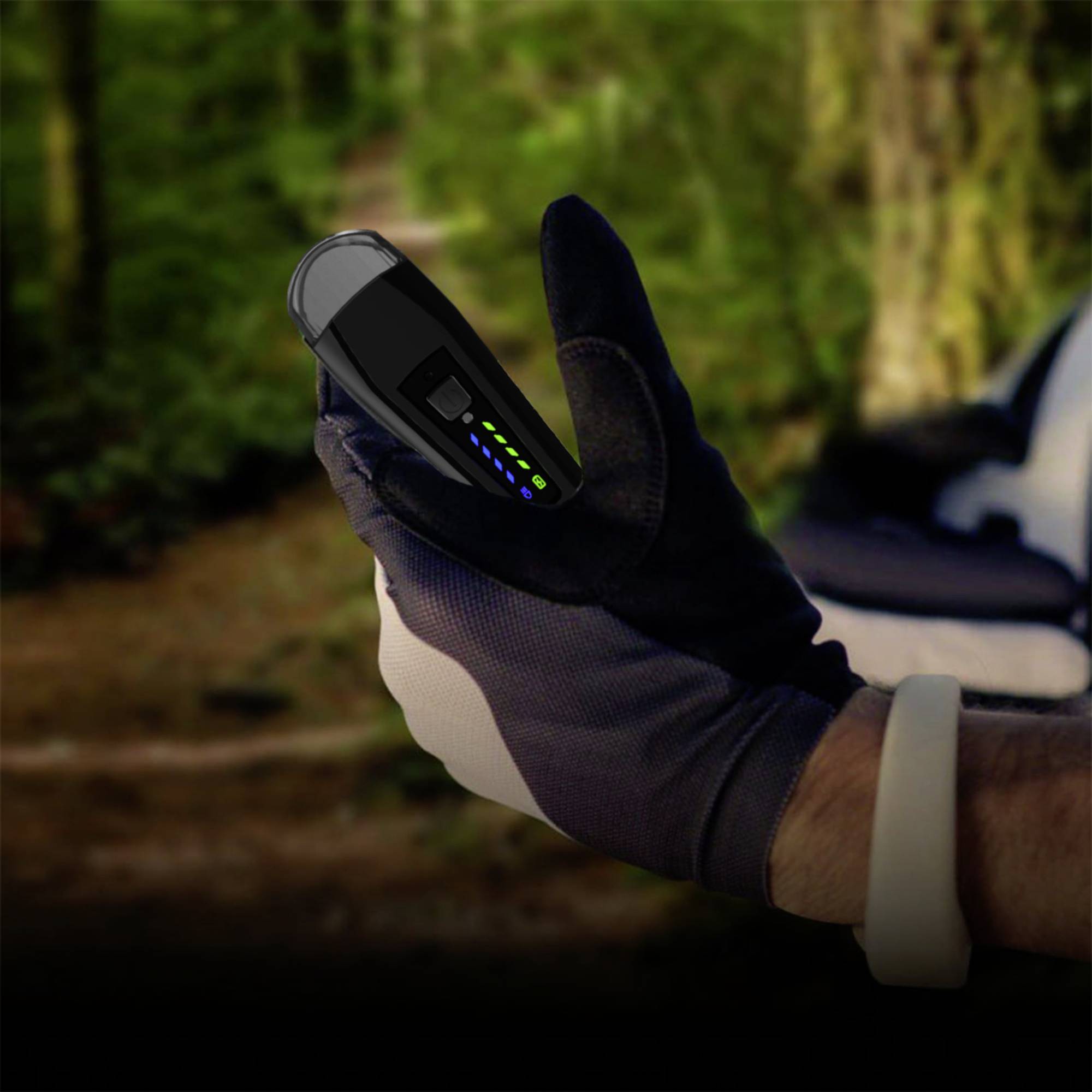 Eine Person in Handschuhen hält ein elektronisches Gerät im Freien. Das Gerät zeigt mehrere leuchtende Anzeigen auf der Seite.