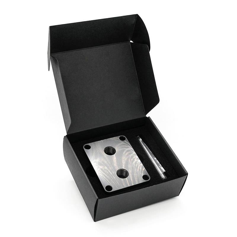 Eine schwarze Geschenkbox mit einer silbernen Metallplatte mit zwei Löchern und einer kleinen Metallstange innen.