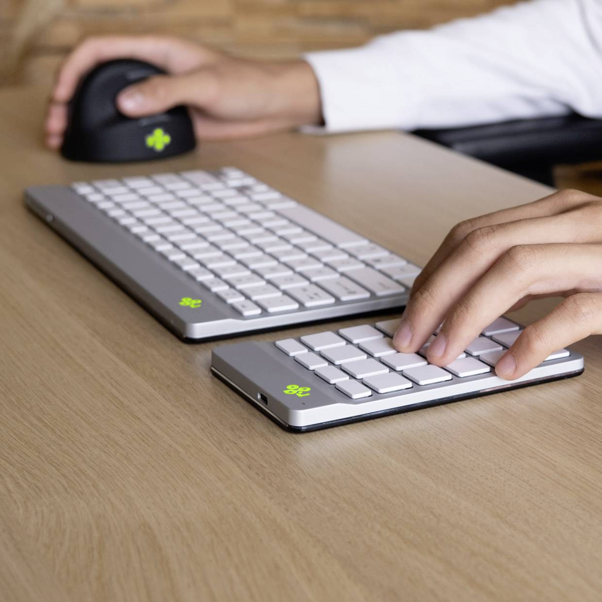 Eine Person tippt auf einer kabellosen Tastatur und nutzt eine kabellose Maus auf einem Schreibtisch.