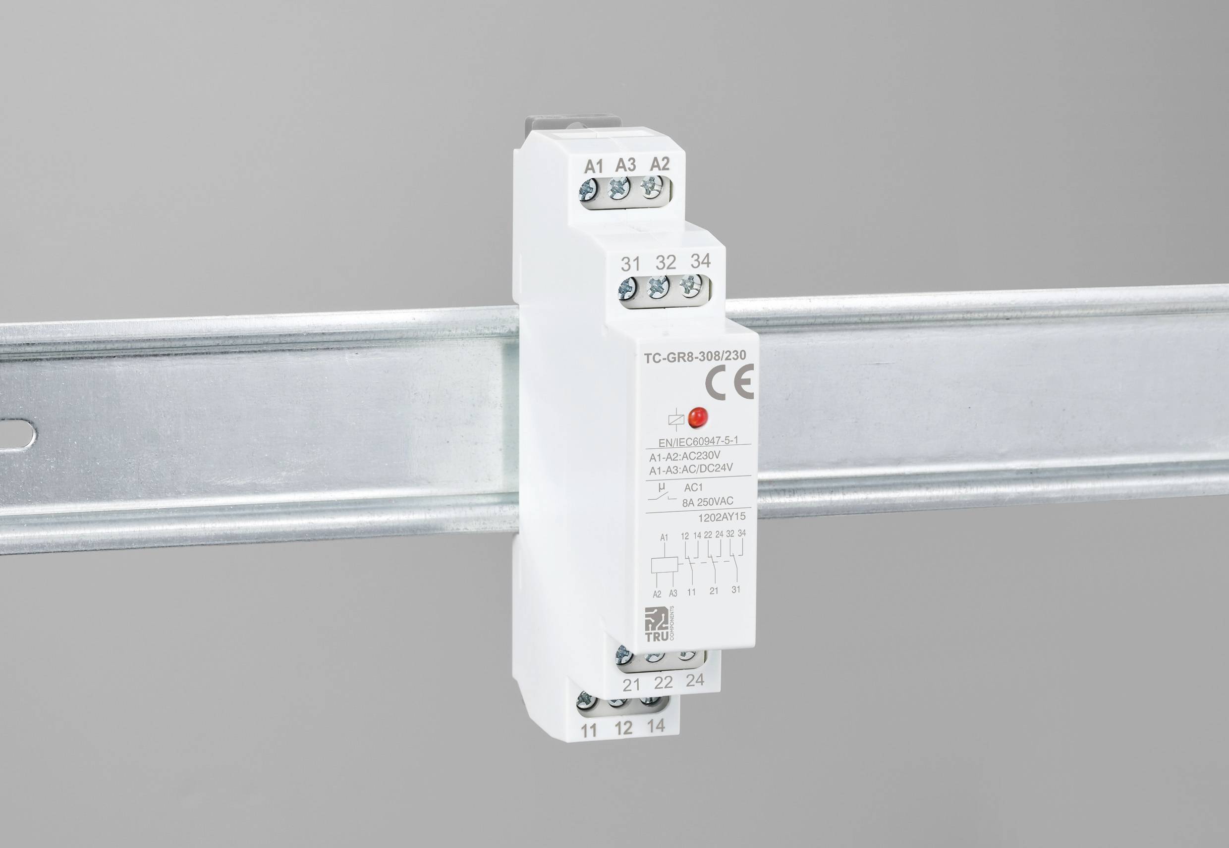 Ein weißes elektrisches Relais ist auf einer Metall-Montageschiene befestigt. Es hat mehrere Anschlüsse und technische Aufdrucke.