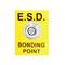 Gelbes Schild mit Aufschrift 'E.S.D. Bonding Point'. Zeigt einen metallischen Kontaktpunkt in der Mitte, spezifiziert für elektrostatische Entladung.