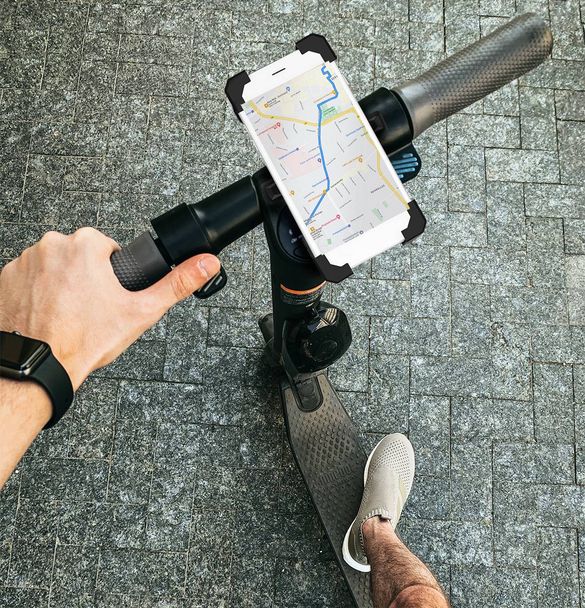Eine Person hält einen E-Scooter-Lenker mit einer Halterung für ein Smartphone, auf dem eine Straßenkarte angezeigt wird.