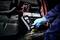 Mechaniker mit blauen Handschuhen misst mit einem Diagnosegerät die Spannung einer Autobatterie im Motorraum.