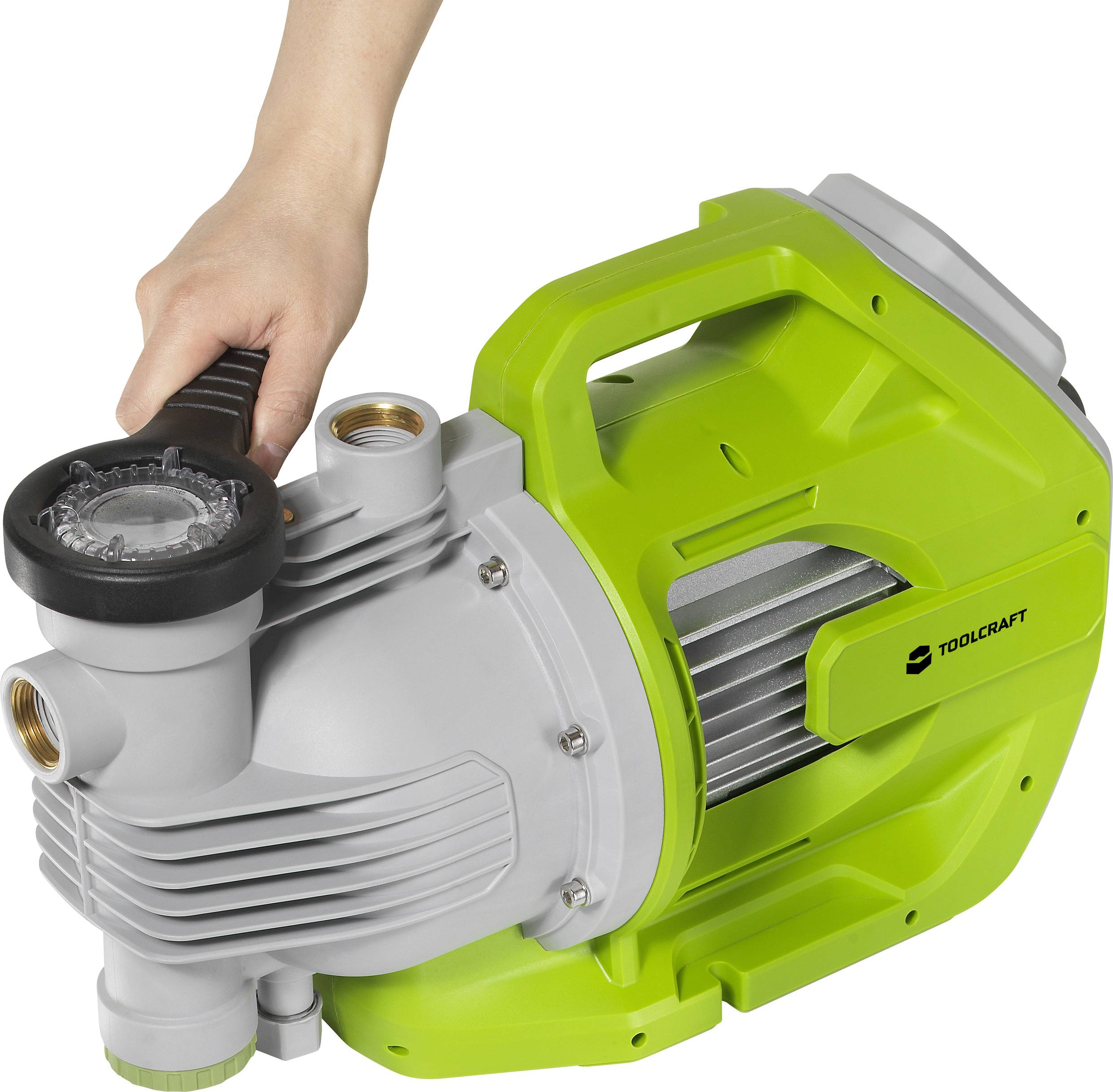 Eine Hand hält eine grüne Wasserpumpe von Toolcraft. Die Pumpe hat silberne Ventile und einen schwarzen Griff, geeignet für Gartenarbeiten.
