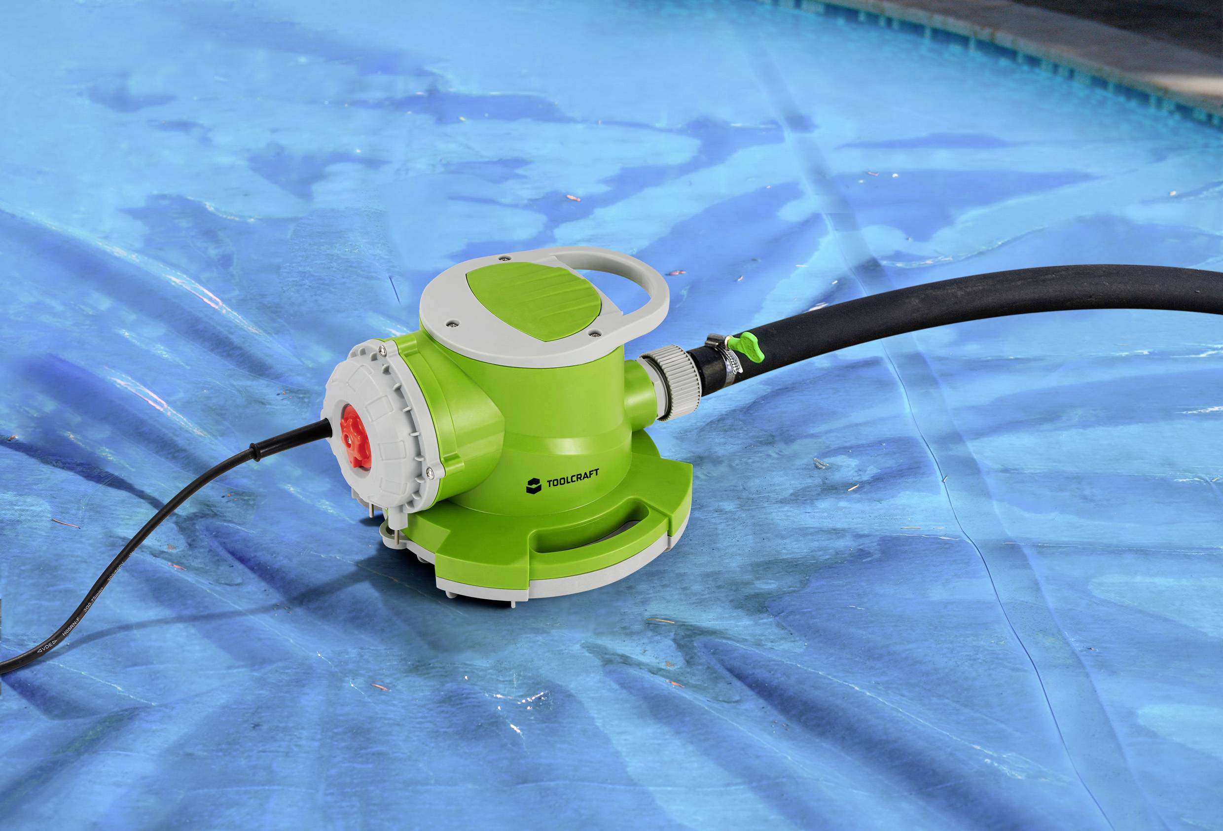 Ein grüner Poolsauger mit Schlauch reinigt den blauen Poolboden. Gerät liegt im Wasser und ist in Betrieb, entfernt Schmutz.