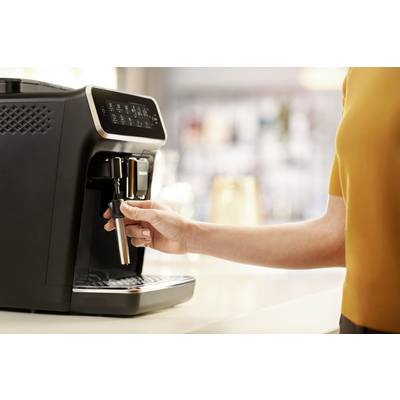 Eine Person bedient eine moderne Kaffeemaschine in einer Küche. Die Hand hält den Hebel, um Kaffee zuzubereiten.