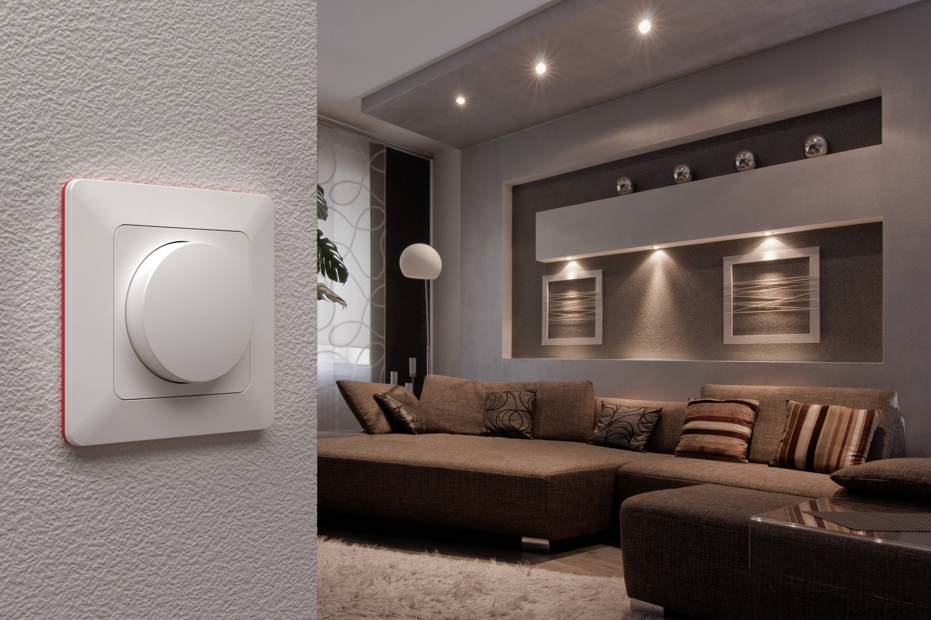 Dimmer-Schalter an der Wand eines modern eingerichteten Wohnzimmers mit Sofa und dekorativen Wandbildern, stimmungsvolle Beleuchtung.