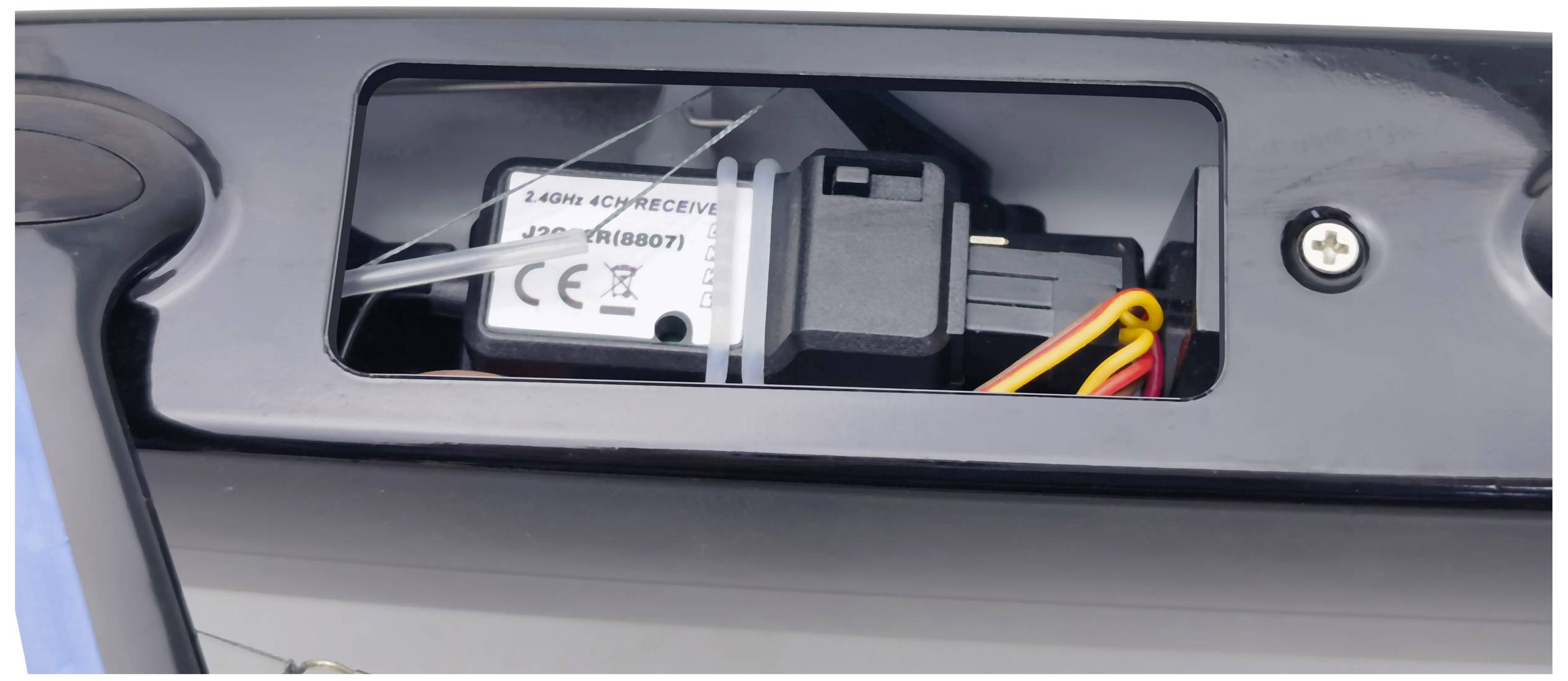 Ein Funkmodul mit der Aufschrift '2.4Ghz 601004882' ist in einem Kunststoffgehäuse montiert, umgeben von Kabeln in einem Gerät.