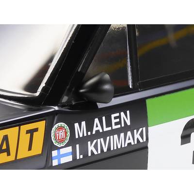 Nahaufnahme eines Rallyeautos mit Namen 'M. Alen' und 'I. Kivimaki' auf der Tür, neben einem Fiat-Logo. Finnische Flagge ist sichtbar.