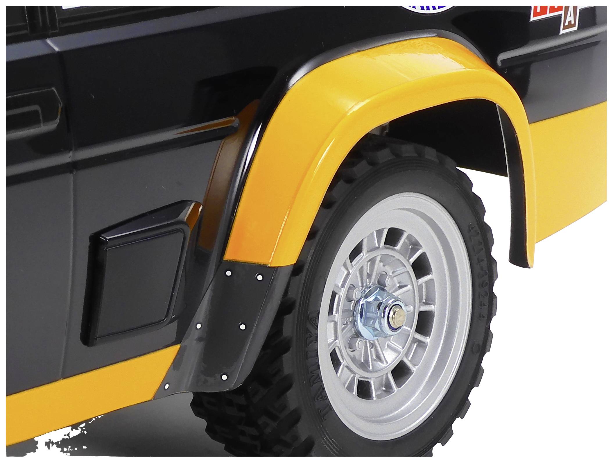 Vorderseite eines gelben und schwarzen Geländewagens, fokussiert auf das Rad mit Stollenreifen und einem glänzenden Raddeckel.