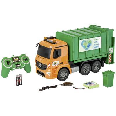Spielzeug-Müllwagen mit Fernsteuerung, Batterien und Ladekabel. Der LKW ist orange mit einem grünen Müllcontainer. Ein Aufkleber zeigt 'Go Green - Reuse Recycle Renew'.